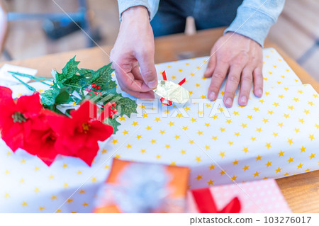 A person who wraps a gift and puts a sticker 103276017