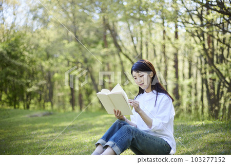 一位三十多歲的日本女性在森林裡看書。 一位三十多歲的日本女性在森林裡看書。 103277152