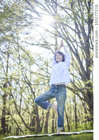 A Japanese woman who enjoys yoga while relaxing in a natural early summer forest 103277218