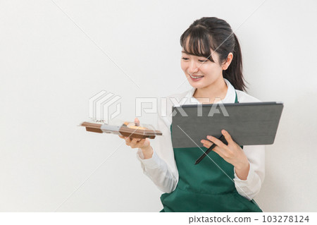 A clerk/part-time woman who manages inventory using a tablet terminal at a convenience store/supermarket A clerk/part-time woman who manages inventory using a tablet terminal at a convenience store/supermarket 103278124