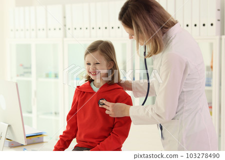 Positive doctor checks heart of little girl with stethoscope 103278490