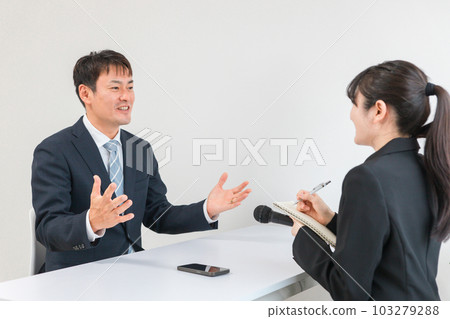 A woman who is a mass media / newspaper reporter interviewing the manager / president who is interviewed A woman who is a mass media / newspaper reporter interviewing the manager / president who is interviewed 103279288