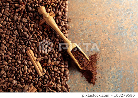 Ground coffee in a spoon and coffee beans with cinnamon and anise on a rusty metal background. 103279590