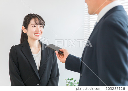 A smiling Asian woman in a suit being interviewed 103282126