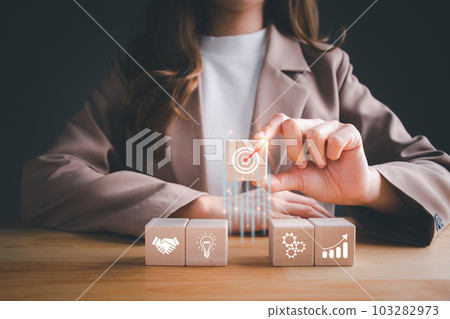 Businesswoman holding arranging wooden block stacking with business strategy and action plan, Goal and targeting, Business development to success and growing concept. 103282973
