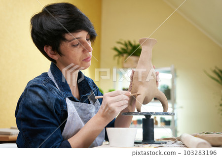 woman sculpts vase from clay by hands, closeup in artistic studio woman sculpts vase from clay by hands, closeup in artistic studio 103283196