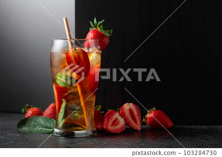 Iced tea or a summer refreshing drink with ice, mint, and strawberries. Iced tea or a summer refreshing drink with ice, mint, and strawberries. 103284730