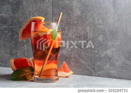 Iced tea with mint and grapefruit on a grey background. Iced tea with mint and grapefruit on a grey background. 103284731