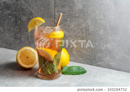 Iced tea with mint and lemon on a grey background. Iced tea with mint and lemon on a grey background. 103284732
