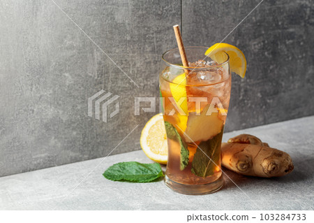 Iced tea with mint, ginger, and lemon on a grey background. Iced tea with mint, ginger, and lemon on a grey background. 103284733