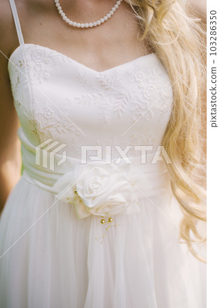 Part of a wedding dress with a flower belt worn by the bride 103286350