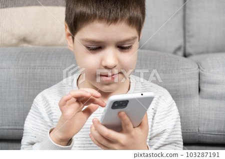 A preschool boy uses a smartphone, plays games on his phone. Screen Time, Parental Controls 103287191