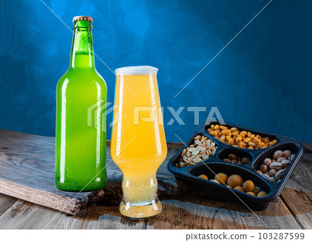 Beer composition. Beer and snacks. Bottle and glass of light beer. Beer and nuts. Still life. 103287599