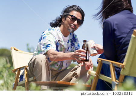 A middle-aged couple sitting under the blue sky and toasting A middle-aged couple sitting under the blue sky and toasting 103288312