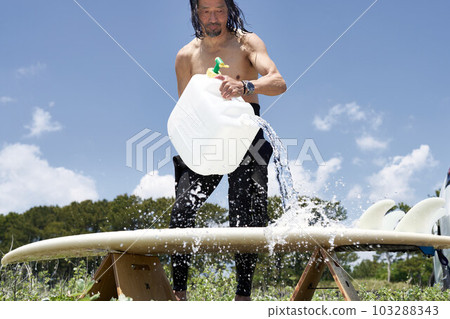 Surfer man washing a surfboard Surfer man washing a surfboard 103288343
