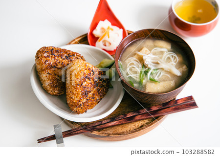 A Japanese set of two grilled rice balls and Nyumen (miso soup with maitake mushrooms, green onions, fried tofu and somen noodles). A Japanese set of two grilled rice balls and Nyumen (miso soup with maitake mushrooms, green onions, fried tofu and somen noodles). 103288582