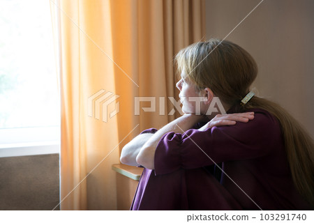 Sad girl sitting by the window 103291740