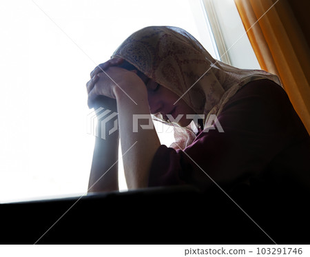Praying woman at the window 103291746