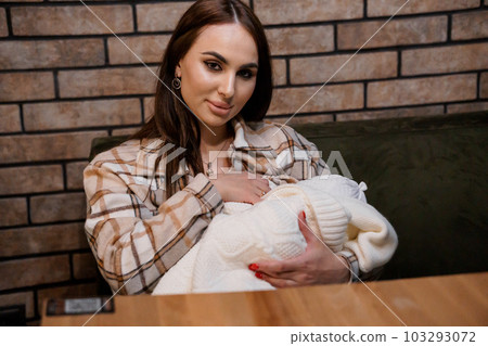 A beautiful girl is holding a baby in her arms. Mother holding baby in the park 103293072
