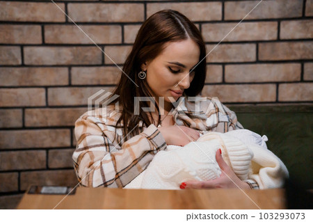 A beautiful girl is holding a baby in her arms. Mother holding baby in the park 103293073