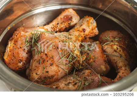 Raw chicken legs with spices. Marinated chicken with rosemary and paprika. Uncooked meat. Raw meat in bowl. Homemade barbecue. Meat and herbs. 103295206