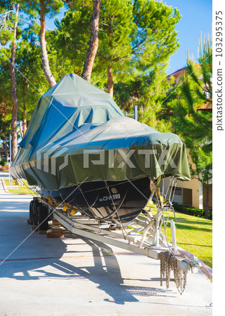 power boat parked covered white protective plastic film New boats in cover casing shrink wrap on sailboat stored for winter 103295375