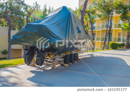 power boat parked covered white protective plastic film New boats in cover casing shrink wrap on sailboat stored for winter 103295377