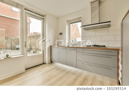 a kitchen with wood flooring and white tile on the walls, in front of an open window looking out onto a brick wall a kitchen with wood flooring and white tile on the walls, in front of an open window looking out onto a brick wall 103295514