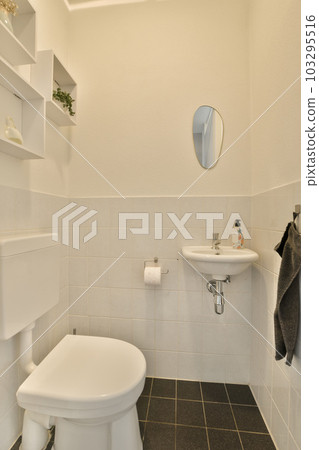 a small bathroom with black and white tiles on the floor, sink, toilet, mirror and towel hanging on the wall 103295516