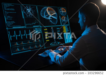 A caucasian man sits in the dark in front of a virtual menu and types on a keyboard. human brain research. A caucasian man sits in the dark in front of a virtual menu and types on a keyboard. human brain research. 103296652