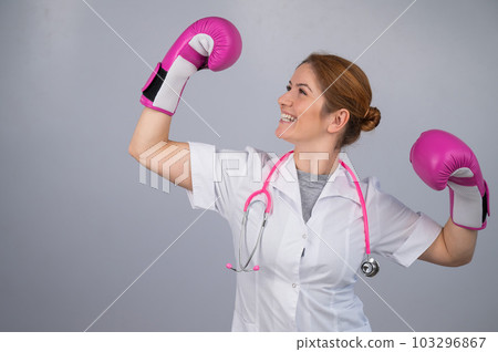 A female doctor raised her hands in pink boxing gloves as a sign of victory over the disease. A female doctor raised her hands in pink boxing gloves as a sign of victory over the disease. 103296867