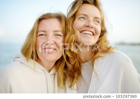 Redhead senior mother and her beautiful adult daughter are walking together and laughing 103297360