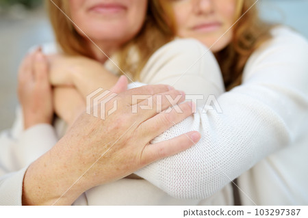 Redhead senior mother and her beautiful adult daughter are walking together and laughing Redhead senior mother and her beautiful adult daughter are walking together and laughing 103297387