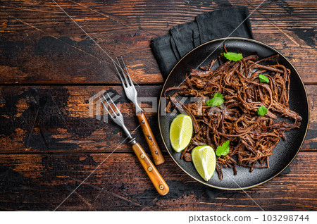 Carnitas in a plate with celery and lime wedges. Wooden background. Top view. Copy space Carnitas in a plate with celery and lime wedges. Wooden background. Top view. Copy space 103298744