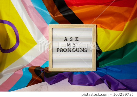 ASK MY PRONOUNS text Neo pronouns concept on Rainbow flag background gender pronouns. Non-binary people rights transgenders. Lgbtq community support assume my gender tolerance equal rights ASK MY PRONOUNS text Neo pronouns concept on Rainbow flag background gender pronouns. Non-binary people rights transgenders. Lgbtq community support assume my gender tolerance equal rights 103299755