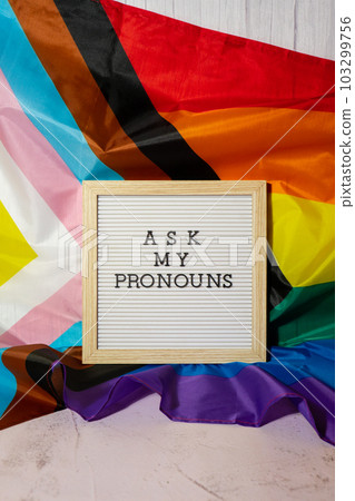 ASK MY PRONOUNS text Neo pronouns concept on Rainbow flag background gender pronouns. Non-binary people rights transgenders. Lgbtq community support assume my gender tolerance equal rights ASK MY PRONOUNS text Neo pronouns concept on Rainbow flag background gender pronouns. Non-binary people rights transgenders. Lgbtq community support assume my gender tolerance equal rights 103299756