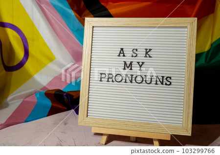 ASK MY PRONOUNS text Neo pronouns concept on Rainbow flag background gender pronouns. Non-binary people rights transgenders. Lgbtq community support assume my gender tolerance equal rights ASK MY PRONOUNS text Neo pronouns concept on Rainbow flag background gender pronouns. Non-binary people rights transgenders. Lgbtq community support assume my gender tolerance equal rights 103299766