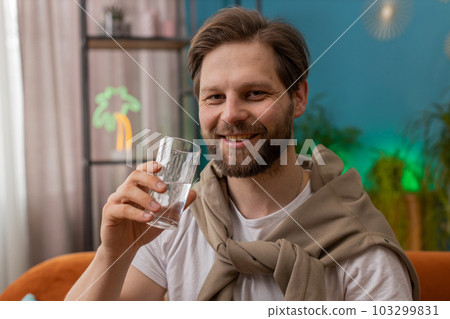 Thirsty Caucasian man sitting at home holding glass of natural aqua make sips drinking still water 103299831