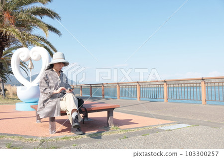 一位女士在海灘旅行時使用手機 103300257