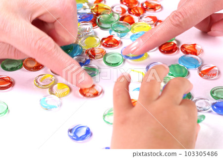 Image of three generations Grandmother, mother and child's hands playing with marbles 103305486
