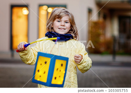 Little preschool kid girl holding selfmade traditional lanterns with candle for St. Martin procession. child happy about children and family parade in kindergarten. German tradition Martinsumzug 103305755