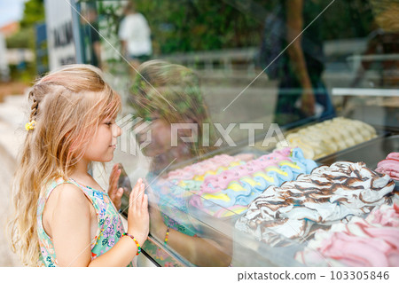 Happy preschool girl choosing and buying ice cream in outdoor stand cafe. Cute child looking at different sorts of icecream. Sweet summer dessert on family vacations. Summertime. 103305846