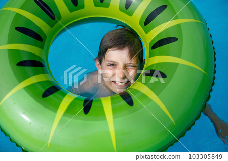 Cool school boy having fun on inflatable rubber circle in outdoor pool. Summer holiday. Summertime kids weekend. Child in swiming pool. Funny kid boy on ring at aquapark on family vacation. Cool school boy having fun on inflatable rubber circle in outdoor pool. Summer holiday. Summertime kids weekend. Child in swiming pool. Funny kid boy on ring at aquapark on family vacation. 103305849