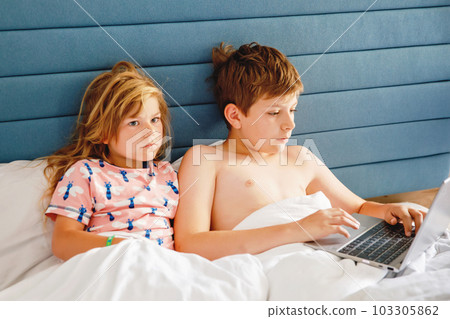 Two children, little girl and school boy learn online at home. Kids, siblings using laptop for homeschooling and distance education. Brother and sister having fun with notebook. Two children, little girl and school boy learn online at home. Kids, siblings using laptop for homeschooling and distance education. Brother and sister having fun with notebook. 103305862
