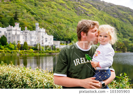 father with little daughter with Kylemore Abbey on background. Man and toddler girl. Family and small children vacations in Ireland father with little daughter with Kylemore Abbey on background. Man and toddler girl. Family and small children vacations in Ireland 103305903