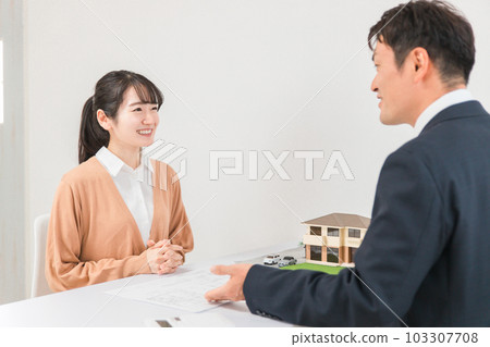 一位女士和一位商人一邊查看藍圖和圖紙，一邊諮詢房屋的改造和翻新 103307708