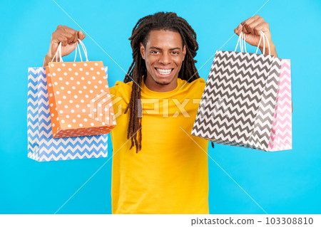 Happy Latin man with dreadlocks raising many shopping bags 103308810