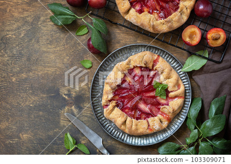 Healthy homemade wholegrain fruit pie, sweet crostata on a rustic table. Vegan vegetarian dessert, plums galette with almonds. View from above. Copy space. 103309071