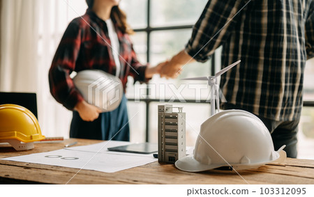 Construction team shake hands greeting start new project plan behind yellow helmet on desk in office center to consults about their building project. 103312095