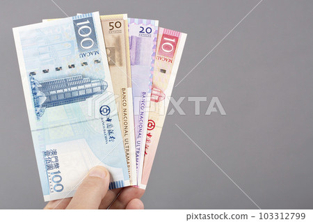 Macanese money in the hand on a gray background 103312799
